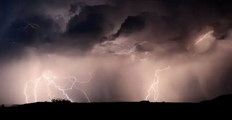 Multiple bolts of lightning striking on a canyon rim