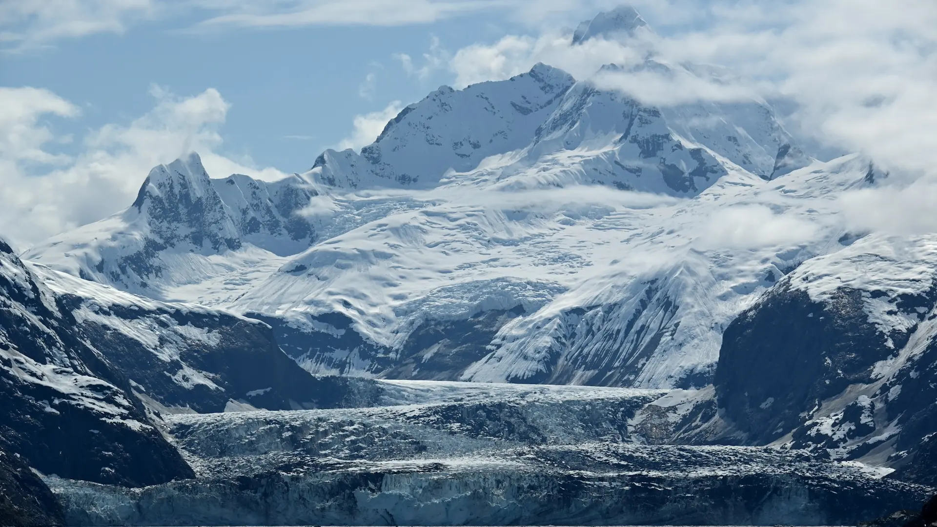 Snow-covered mountains rise above a tidewater glacier in Glacier Bay National Park.