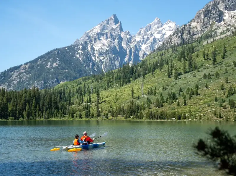 Two kayakers on a lake with a mountain in the background