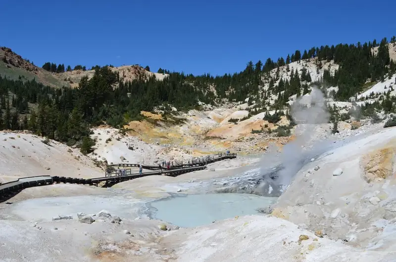 A boardwalk passes through a colorful, steaming hydrothermal basin.