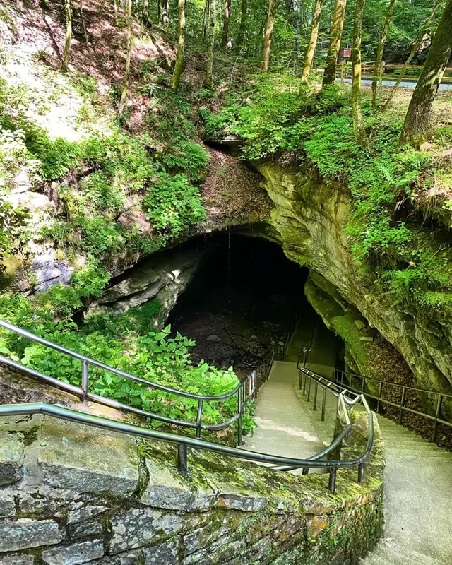 A long staircase travels down a slope into the dark cave opening. 