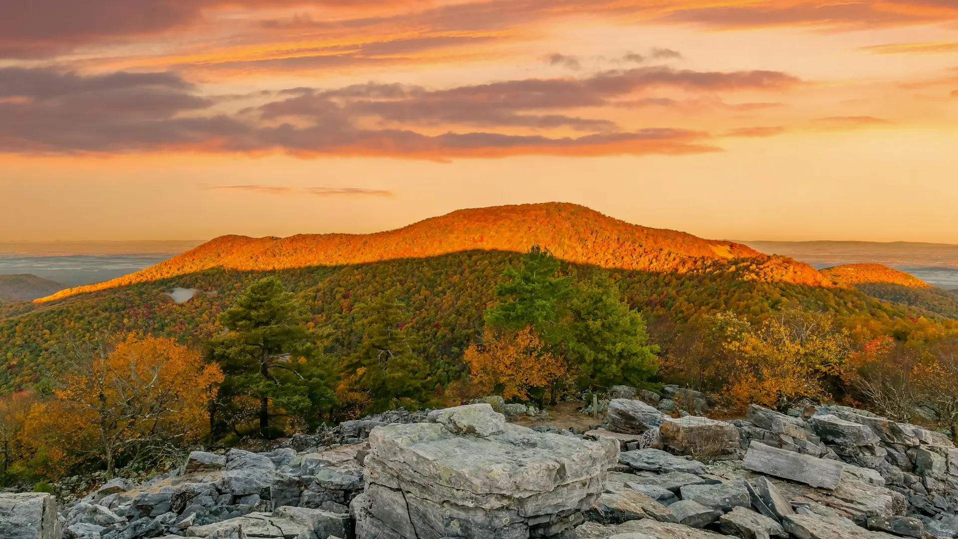 A view of a mountain with a sunset in the background