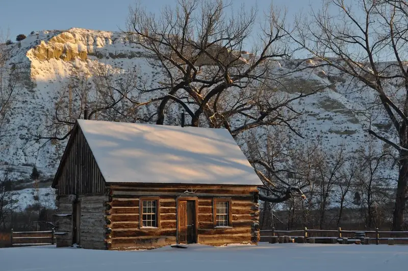 The rising sun casts light on Roosevelt's snow-covered cabin.