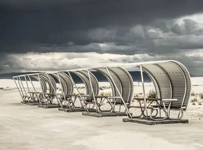a curved metal structure covers picnic table on a concrete pad.